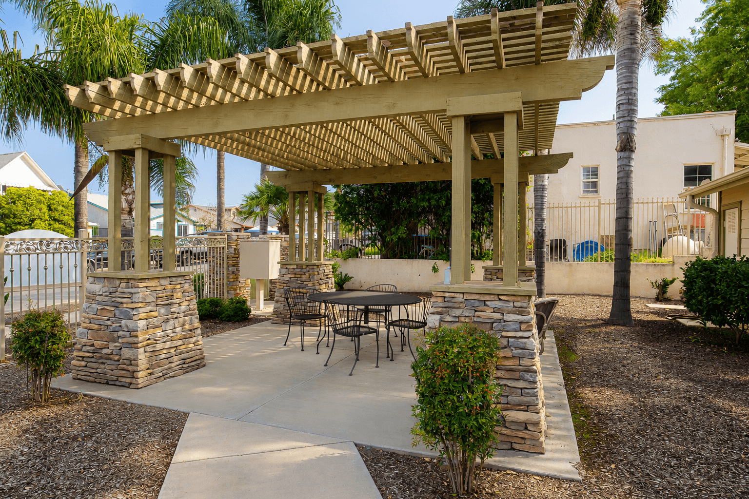A patio with a table and chairs under a wooden pergola.